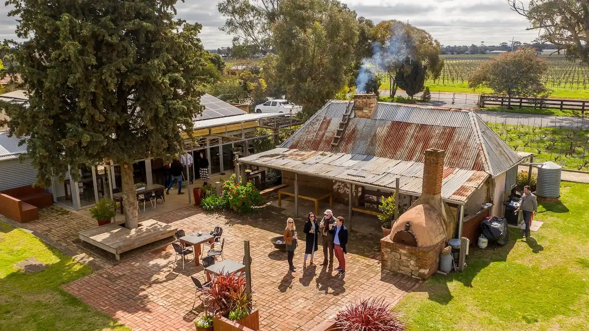 Aerial view of Silvertracre winery’s rustic courtyard with visitors, a brick outdoor patio, historic buildings, and surrounding vineyards
